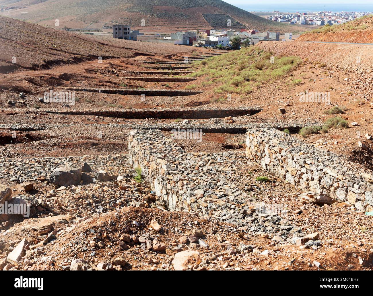 Controllare le dighe che attraversano la valle per controllare il rischio di alluvioni flash giù ripide colline, Mirleft, Marocco, Nord Africa Foto Stock