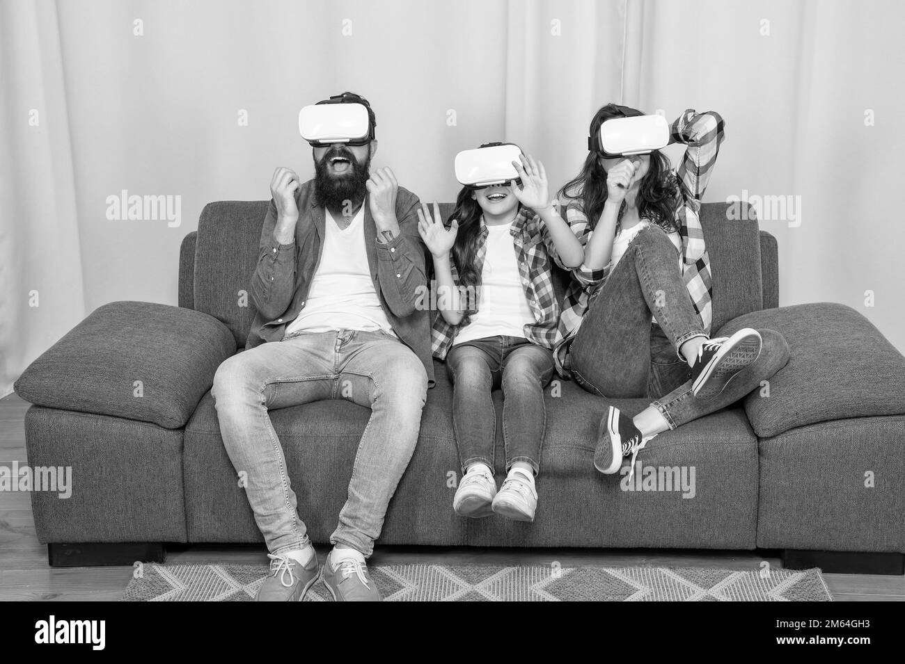 la famiglia felice indossa occhiali vr seduti sul divano a casa, tecnologia futura Foto Stock