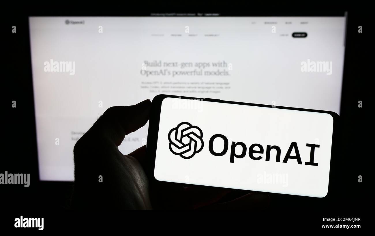 Persona che tiene il cellulare con il logo della società americana di intelligenza artificiale OpenAI LLC sullo schermo di fronte alla pagina web. Messa a fuoco sul display del telefono. Foto Stock