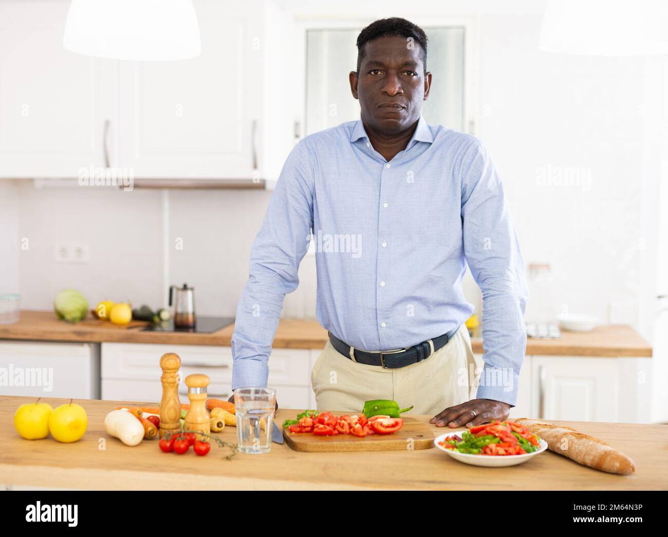 Uomo afroamericano che prepara insalata di verdure in cucina Foto Stock