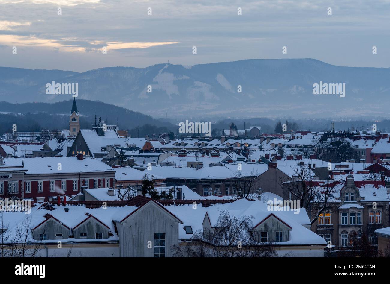 Paesaggio urbano di Cesky Tesin, regione della slesia Morava, Repubblica Ceca, tetti innevati e montagne beskid sullo sfondo Foto Stock