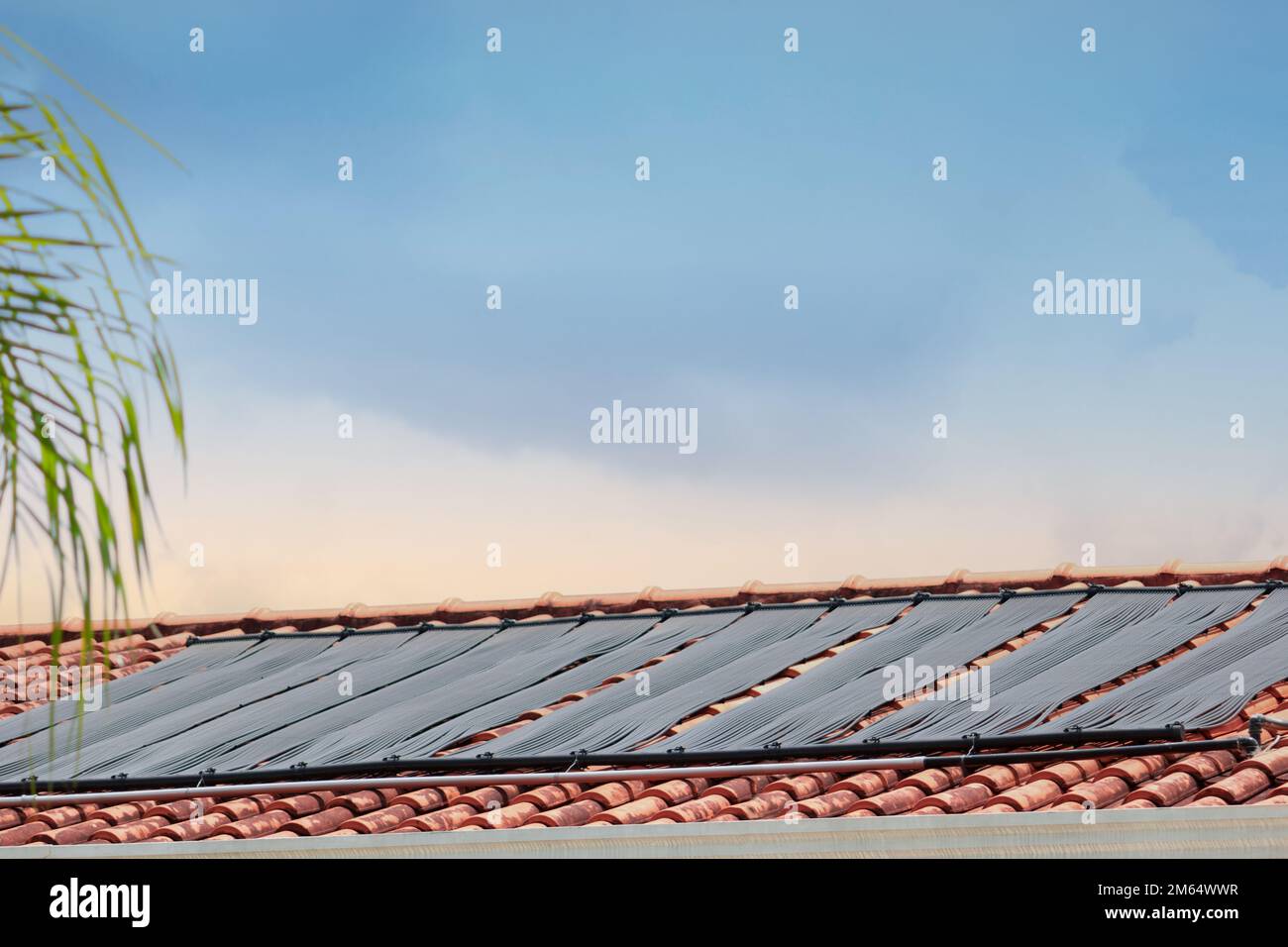 Sistema di riscaldamento dell'acqua sul tetto della casa in una giornata di sole e nuvoloso. Immagine del concetto rinnovabile. Foto Stock