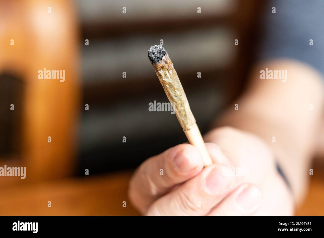Dito che tiene la sigaretta di cannabis spesa e pronto per essere fumato Foto Stock