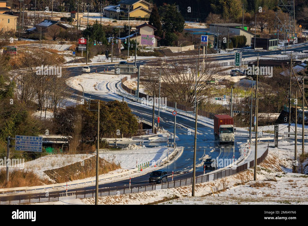 Sekigahara, Giappone - 25 dicembre 2022: Autocarro da carico su strada ventosa attraverso il paesaggio innevato nelle giornate di sole Foto Stock