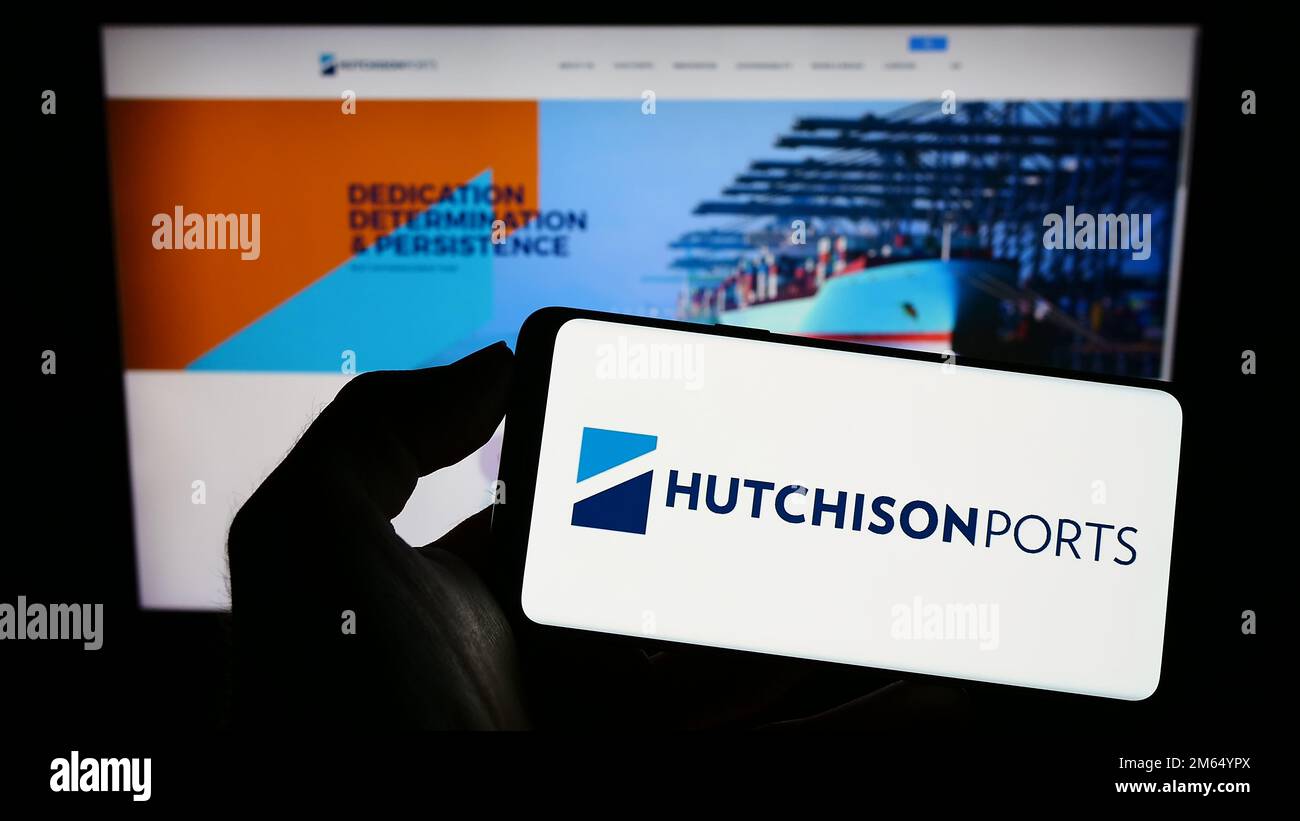 Persona che detiene il telefono cellulare con il logo della società Hutchison Port Holdings Limited sullo schermo di fronte alla pagina web aziendale. Messa a fuoco sul display del telefono. Foto Stock