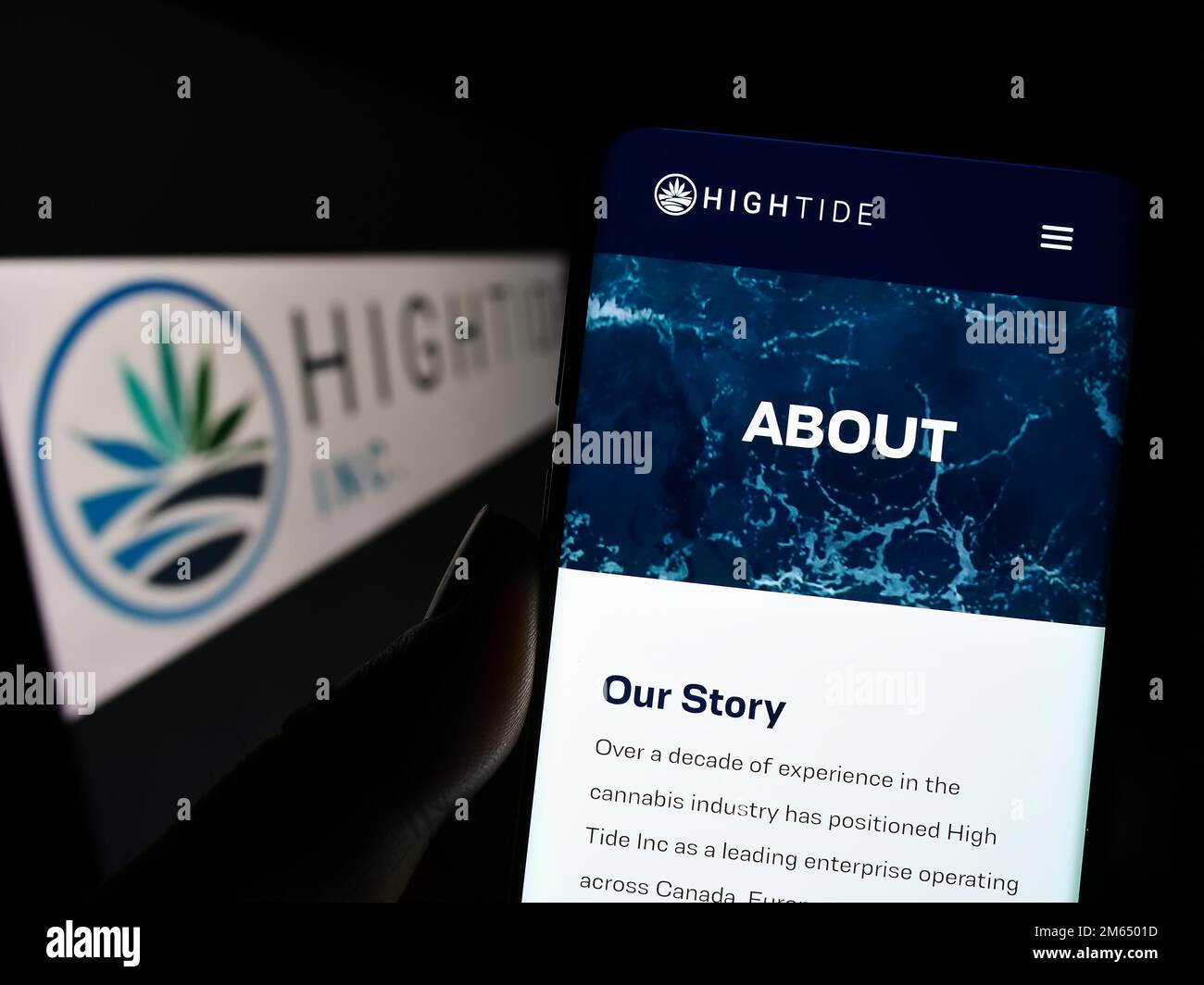 Persona che tiene il cellulare con il sito web della società canadese di cannabis High Tide Inc. Sullo schermo di fronte al logo. Messa a fuoco al centro del display del telefono. Foto Stock