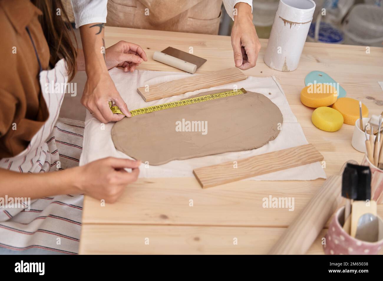 Donna che misura l'argilla con un metro in un laboratorio di ceramica. Donna che impara a lavorare la classe Crafts argilla. Foto Stock