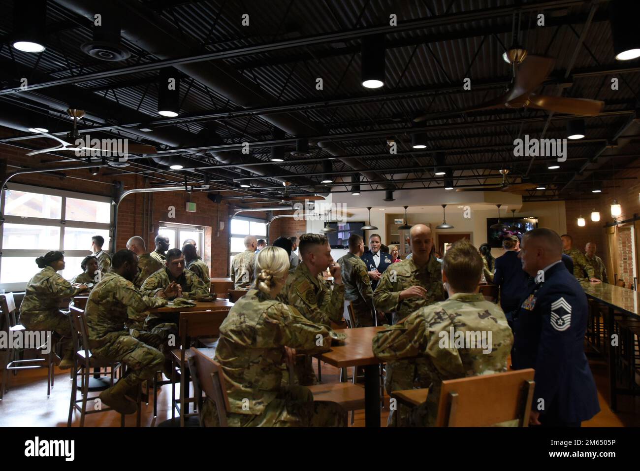 STATI UNITI Gli airmen assegnati alla Guardia Nazionale dell'aria del North Carolina godono del cibo, delle bevande e della conversazione durante una grandiosa apertura dell'Epic Center che si tiene presso la base della Guardia Nazionale dell'aria del North Carolina, all'Aeroporto Internazionale Douglas di Charlotte, il 2 aprile 2022. L'Epic Center vanta molto spazio per cerimonie, grandi riunioni al coperto e all'aperto, nonché un caminetto all'aperto con copertura e riscaldatori. Foto Stock