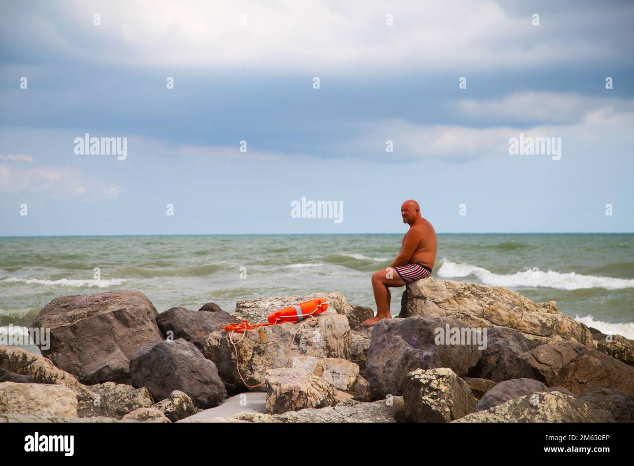 l'uomo sulle rocce guarda al mare Foto Stock