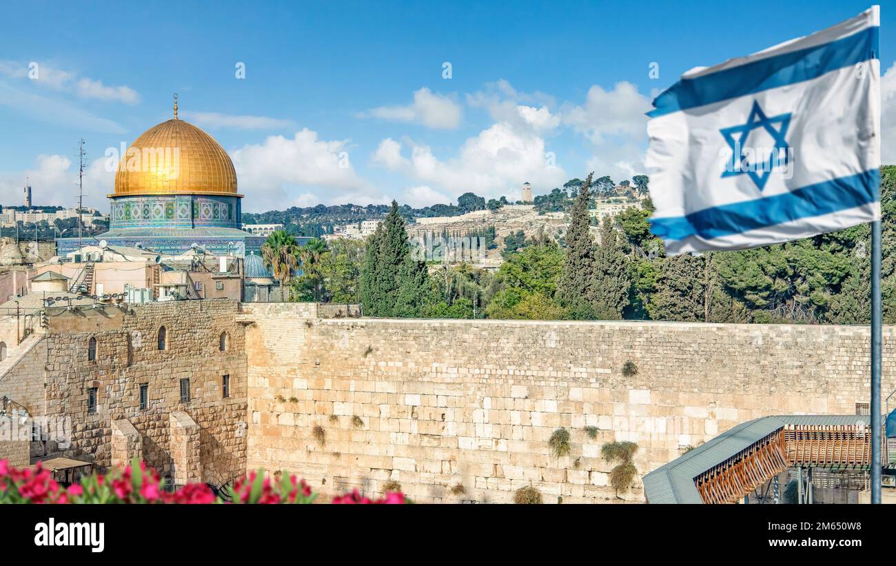 Una bandiera israeliana soffia mentre i credenti ortodossi ebrei leggono la Torah e pregano di fronte al Muro Occidentale, noto anche come Muro del Pianto nella Città Vecchia di Gerusalemme Foto Stock