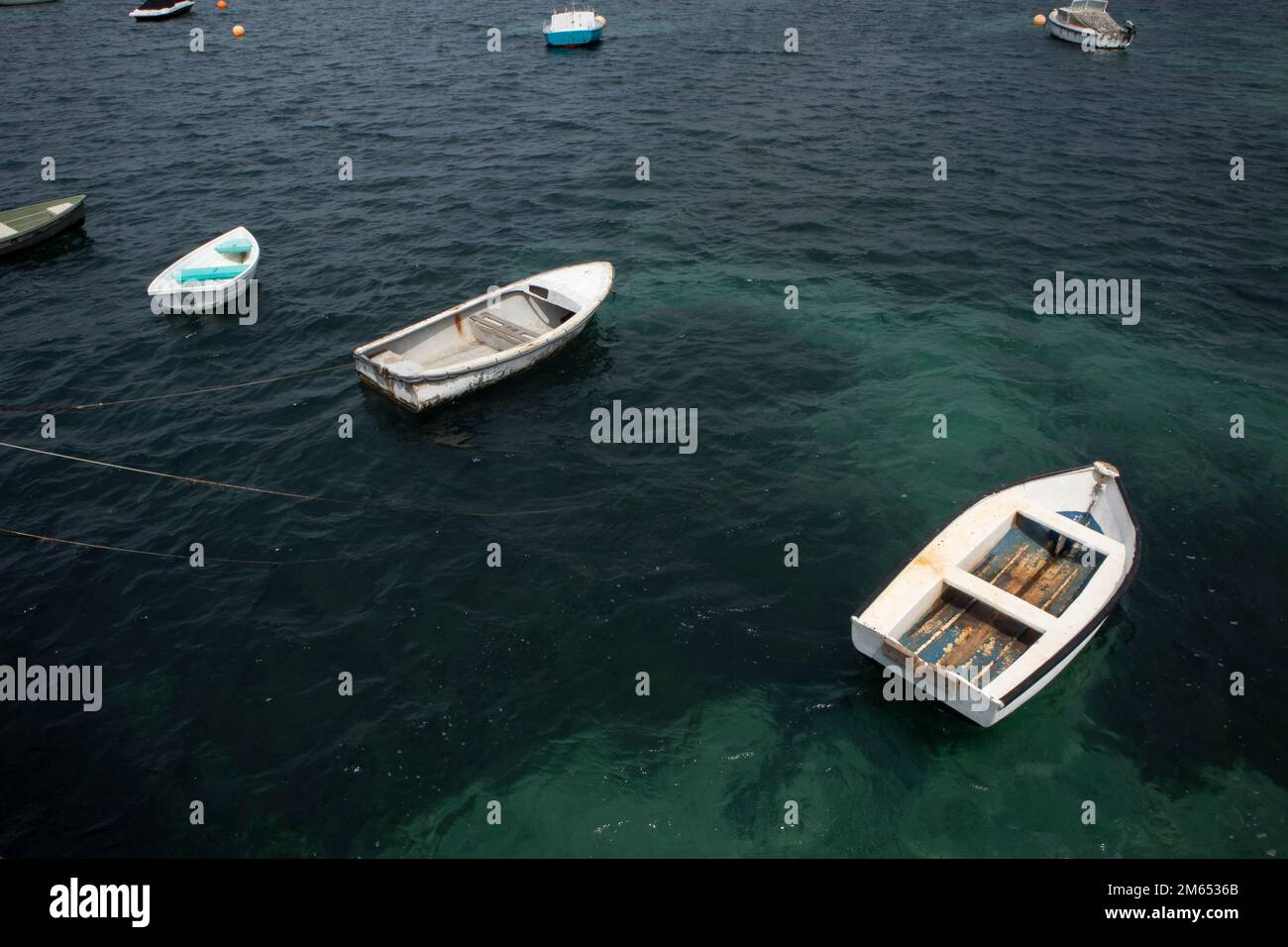 Piccole barche a remi all'ancora in acqua di mare Foto Stock