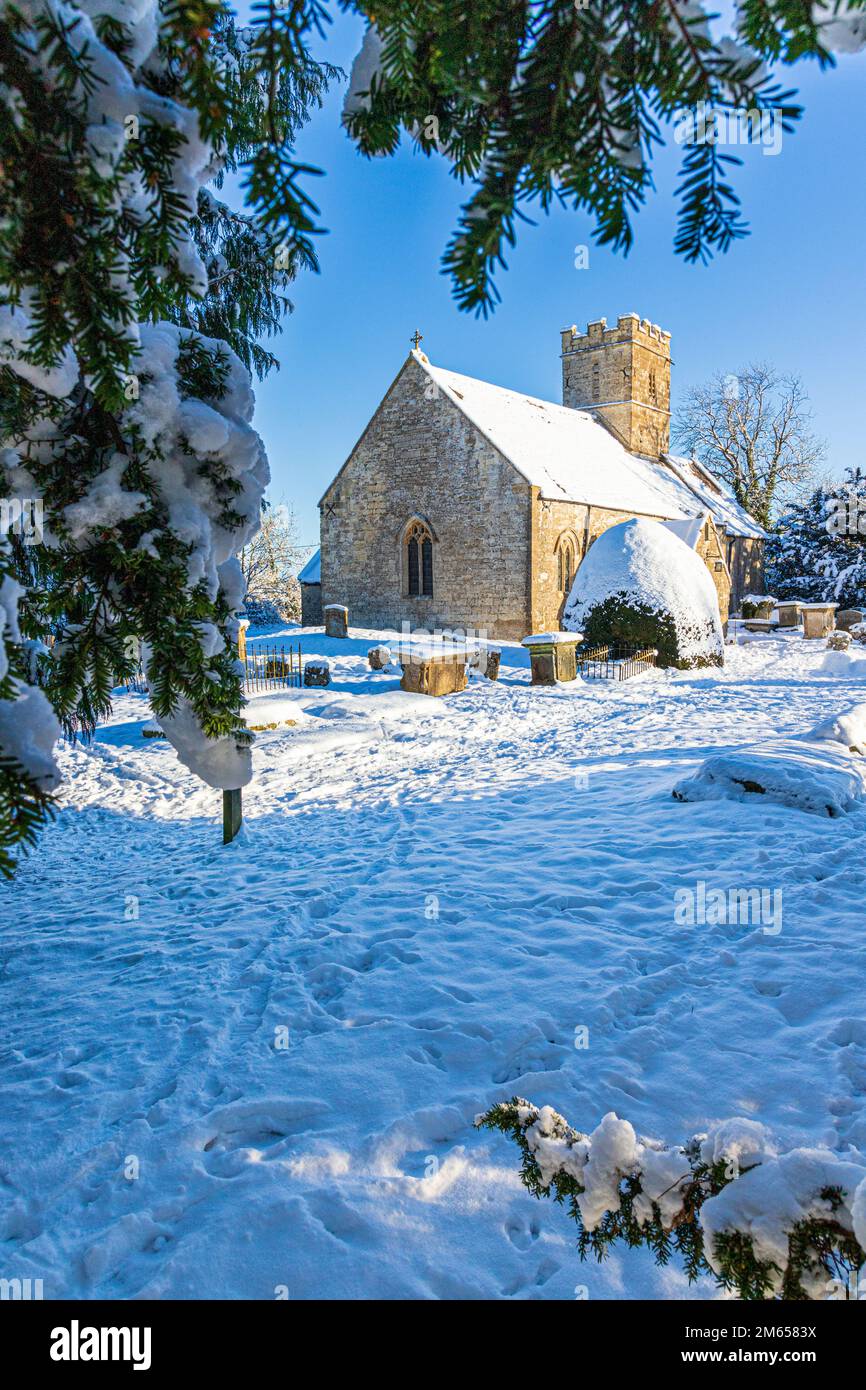 Neve d'inverno all'inizio della chiesa di St Michael & All Angels del 12th ° secolo nel villaggio di Cotswold di Bridpsfield, Gloucestershire, Inghilterra UK Foto Stock