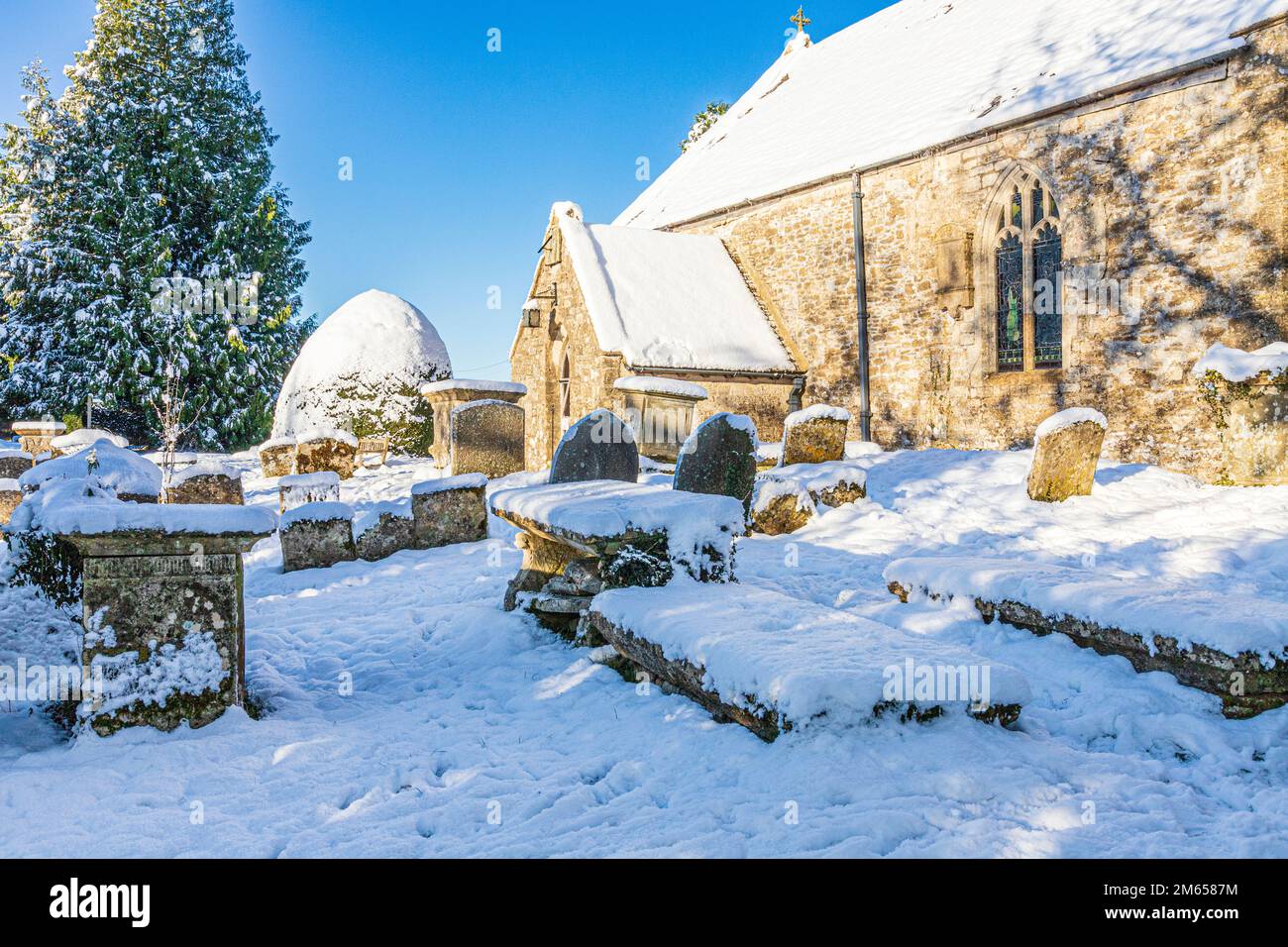 Neve d'inverno all'inizio della chiesa di St Michael & All Angels del 12th ° secolo nel villaggio di Cotswold di Bridpsfield, Gloucestershire, Inghilterra UK Foto Stock