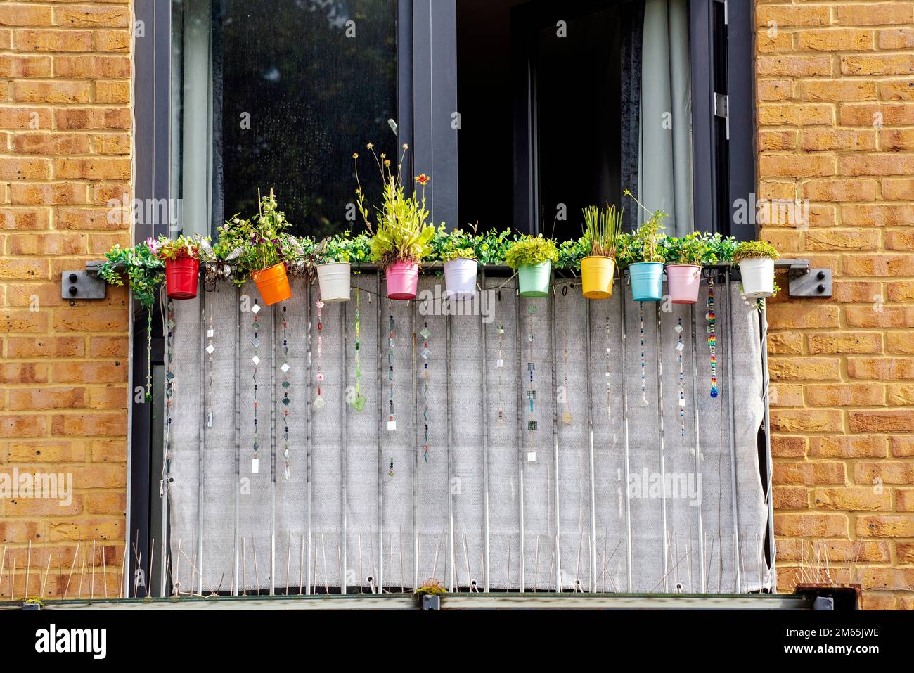 Vasi di fiori di plastica colorati appesi al balcone, Vauxhall Foto Stock