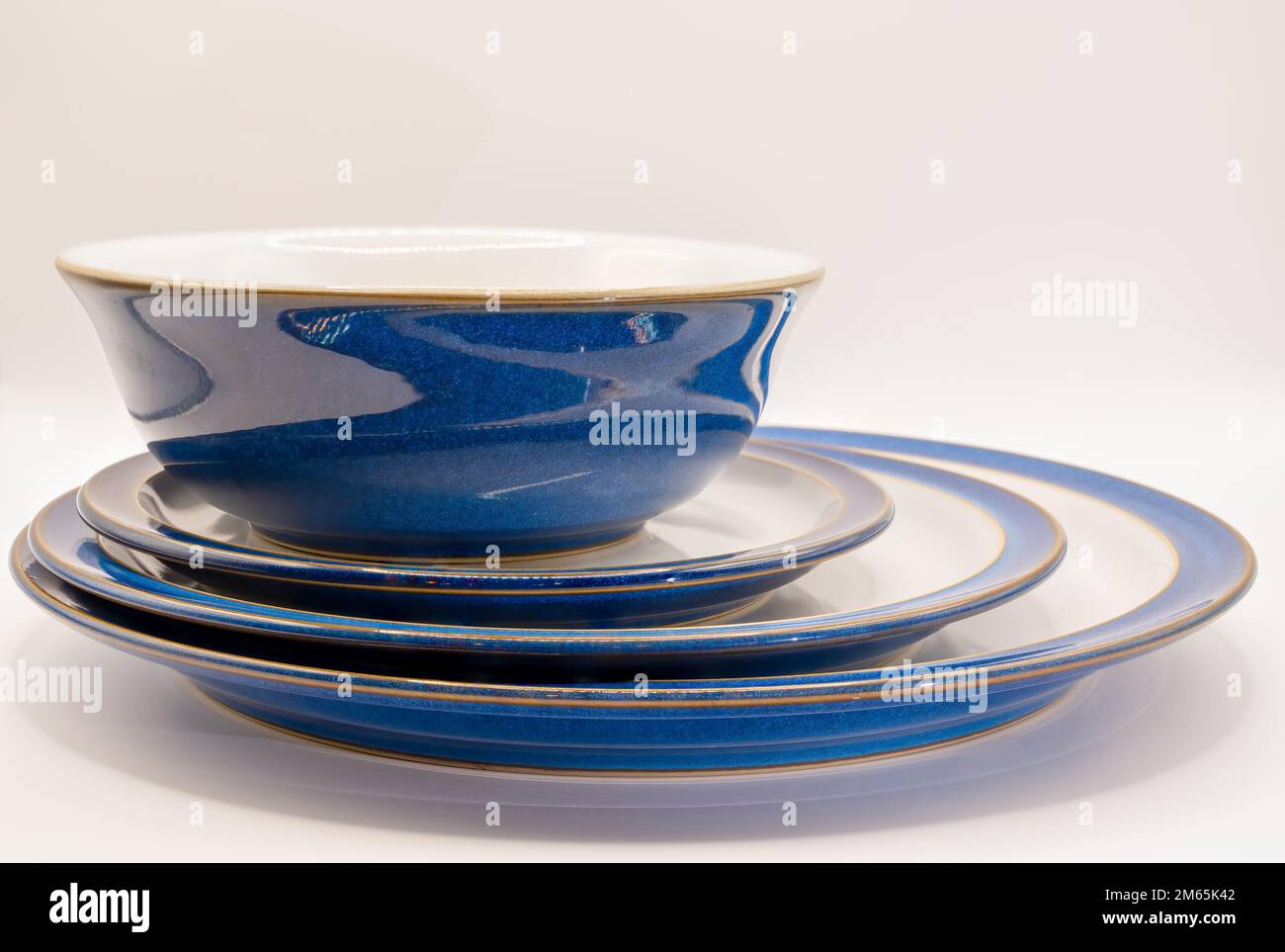 posto a sinistra una ciotola e tre formati di piatti in bianco con bordi e bordi blu e una finitura dorata Foto Stock