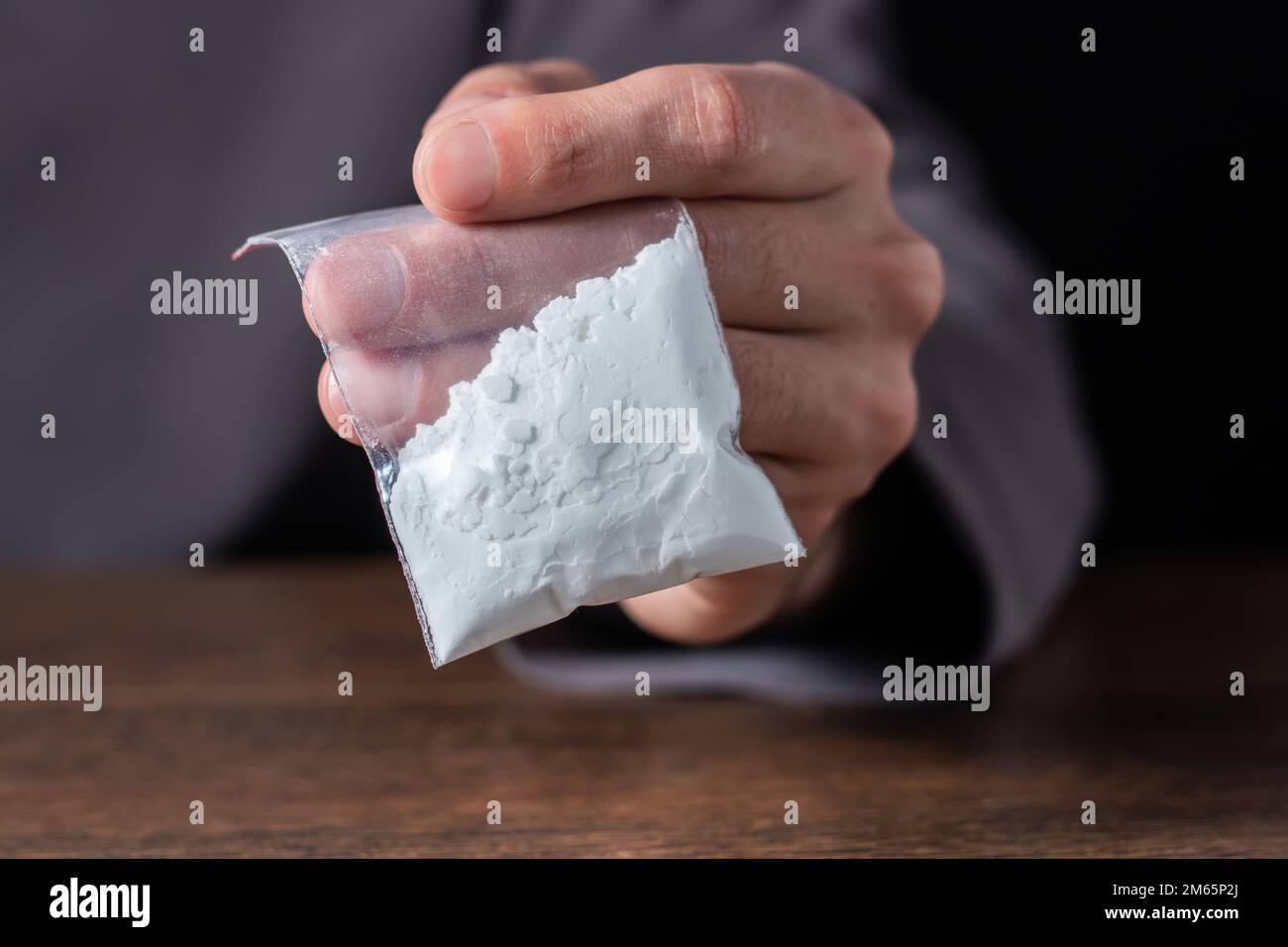 Concetto di tossicodipendenza. La mano dell'uomo tiene il pacchetto o il sacchetto di plastica con la cocaina o altre droghe, l'abuso della droga e il concetto di dipendenza di pericolo. Foto Stock