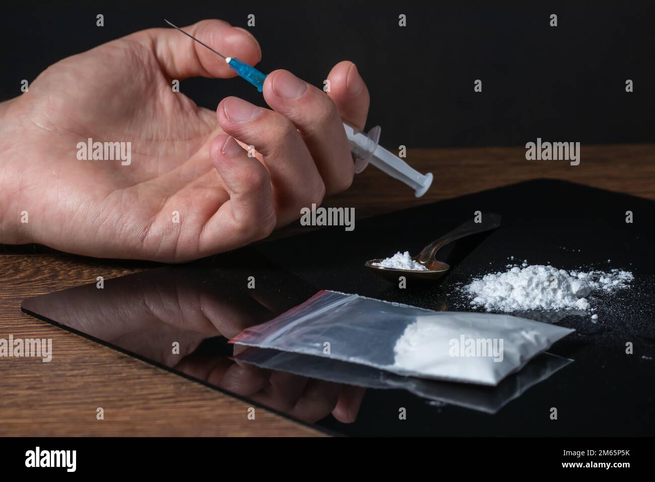 Siringa del farmaco in mano. Un tossicodipendente con un'altra dose del farmaco nella siringa. Guy dipendente, il concetto di anti-droga. tossicodipendente maschile. Foto Stock