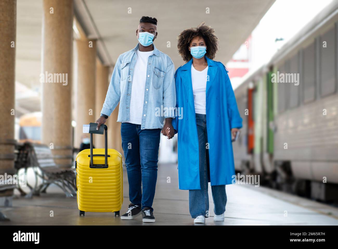 African Amerian Coppia indossando maschere mediche protettive a piedi alla stazione ferroviaria Foto Stock