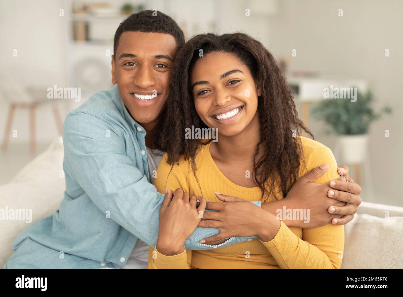 Sorridente uomo afroamericano millenario che abbraccia donna, godere romantico, amore, tempo libero e guardando la macchina fotografica Foto Stock