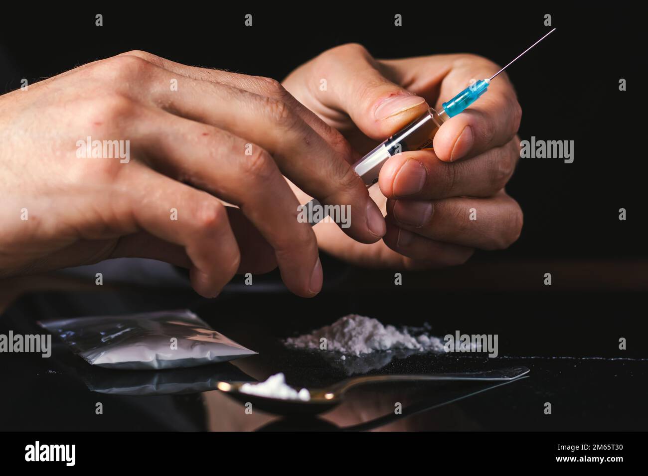 Siringa del farmaco in mano. Un tossicodipendente con un'altra dose del farmaco nella siringa. Guy dipendente, il concetto di anti-droga. tossicodipendente maschile. Foto Stock