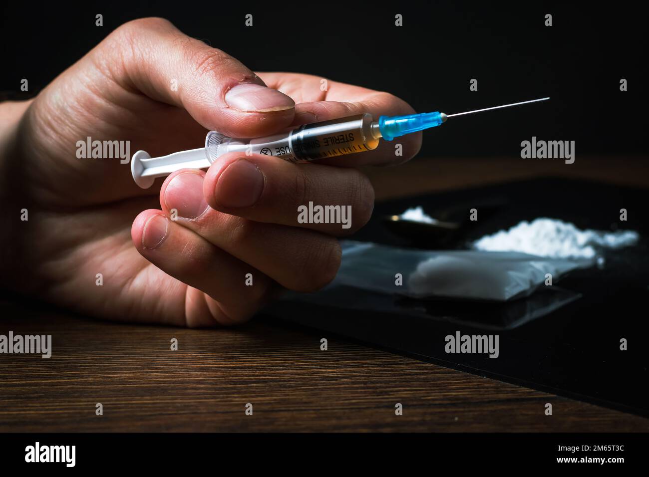 Siringa del farmaco in mano. Un tossicodipendente con un'altra dose del farmaco nella siringa. Guy dipendente, il concetto di anti-droga. tossicodipendente maschile. Foto Stock