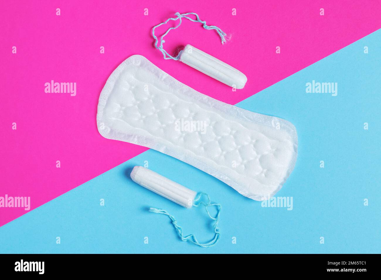 donne tamponi e tamponi - tamponi sanitari si trova accanto a un tampone su uno sfondo isolato su uno sfondo rosa e blu. Igiene femminile e mestruale per Foto Stock