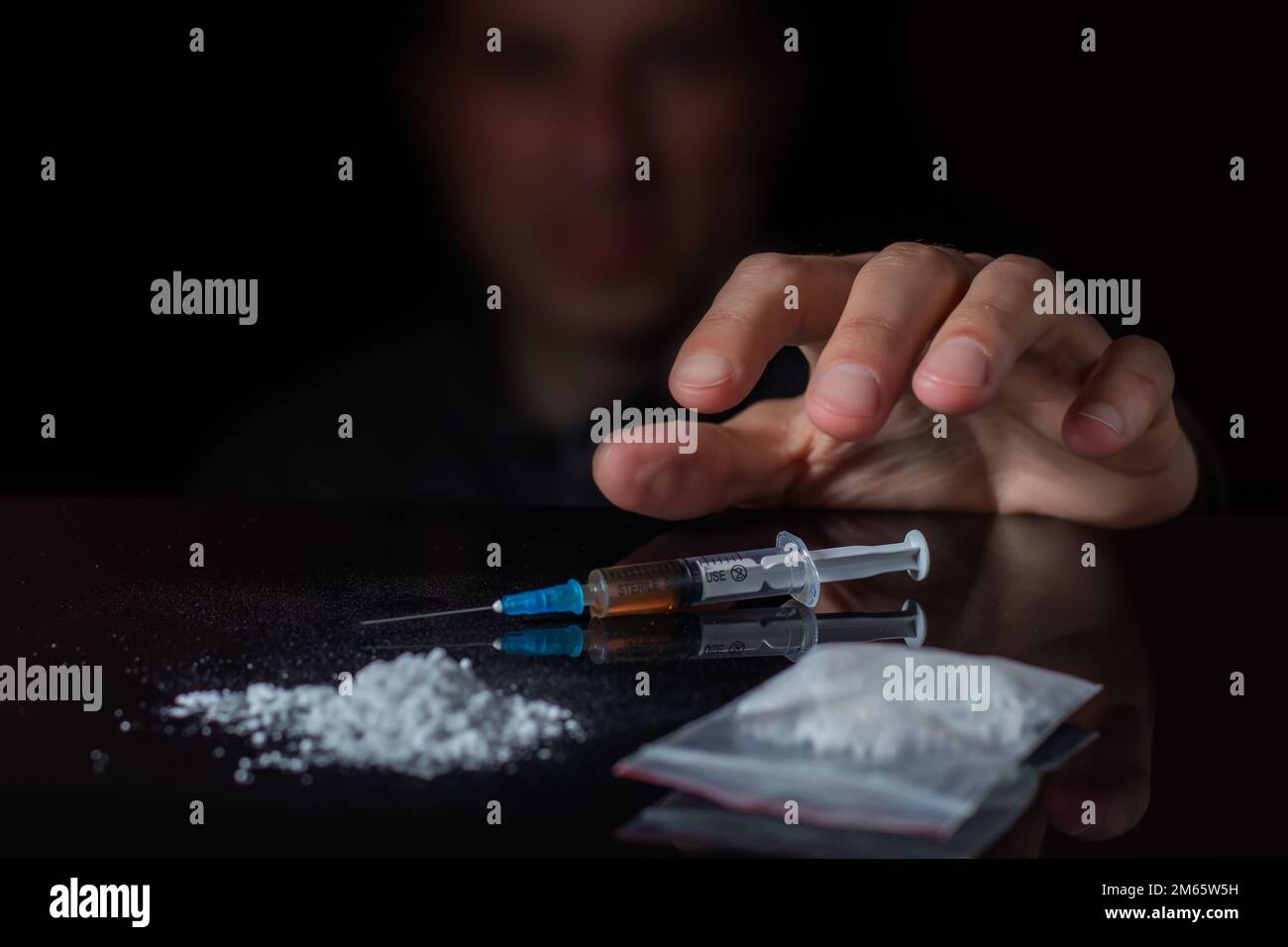 Il concetto di anti-droga. Il tossicodipendente raggiunge un'altra dose del farmaco nella siringa. Ragazzo addicted, tossicodipendente maschile, siringa di droga Foto Stock