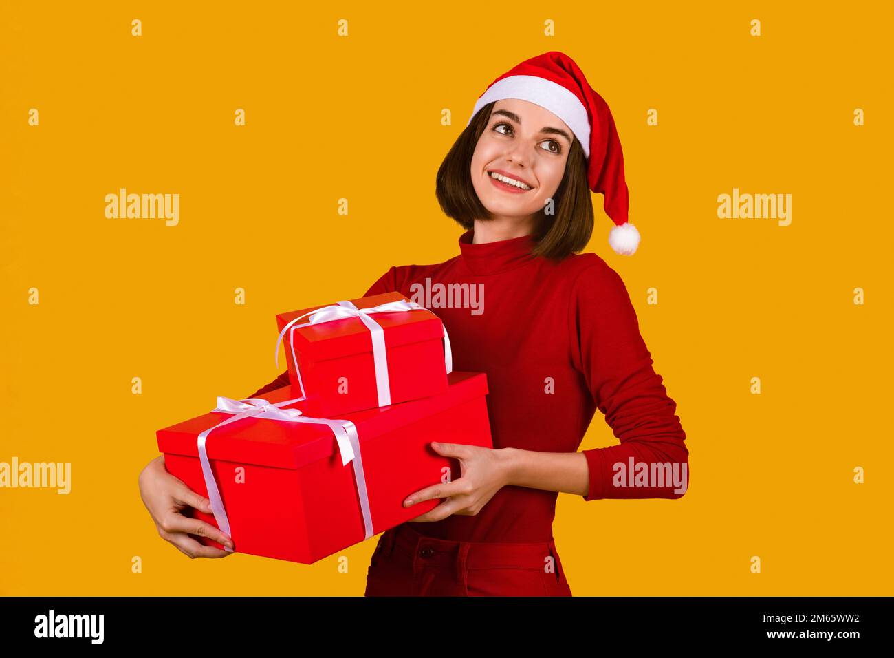 Felice giovane donna in cappello di Santa che tiene regali di Natale Foto Stock
