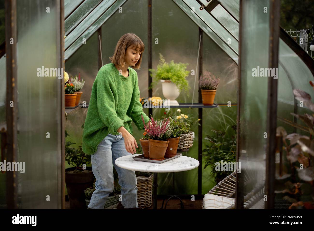 Donna con piante in serra Foto Stock