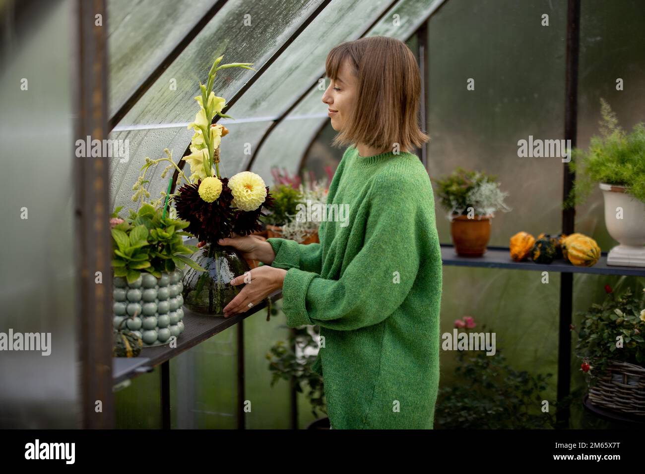 Donna con fiori in serra Foto Stock
