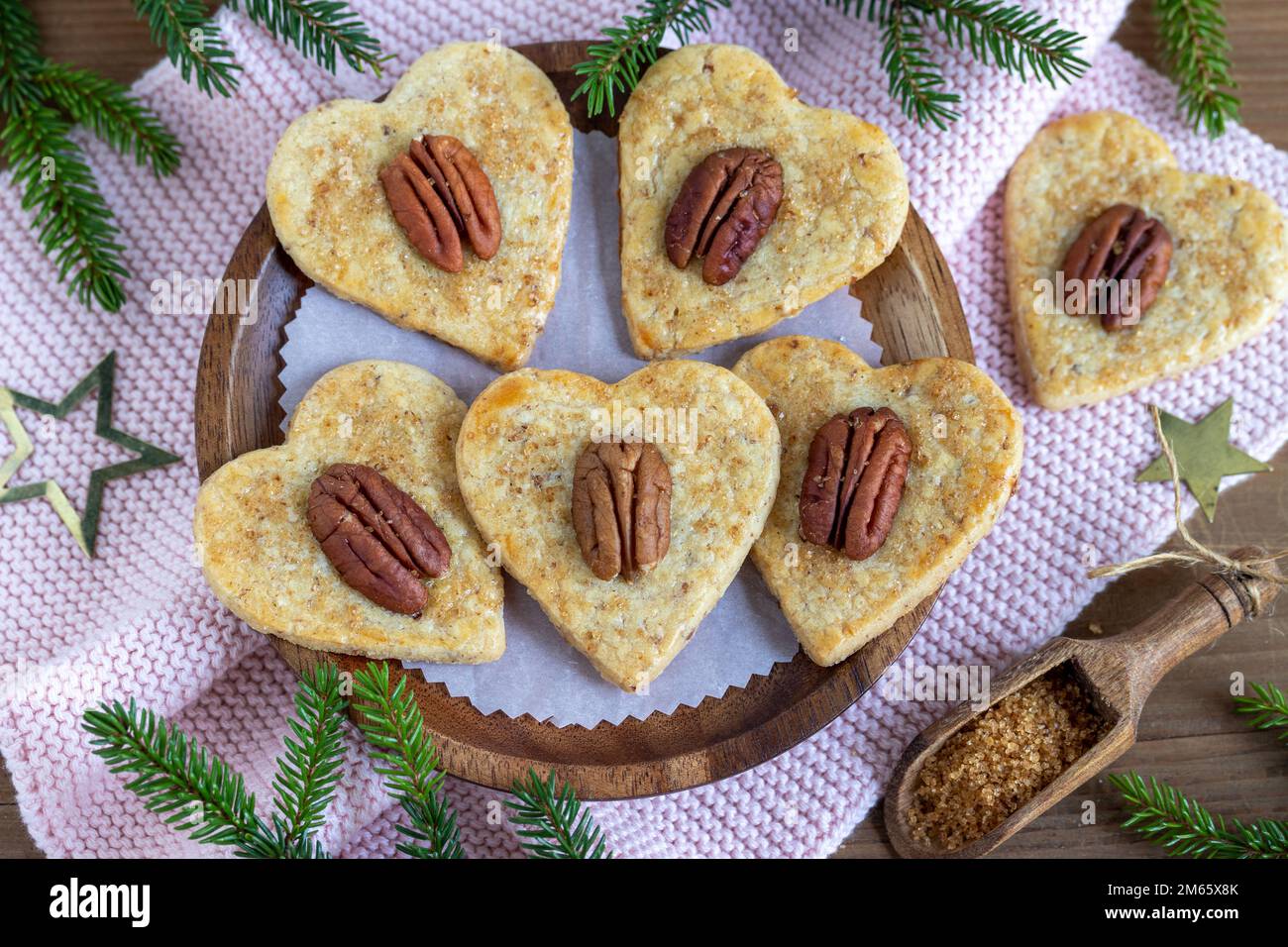 biscotti di natale cuori di noci pecan con zucchero di canna su piatto di legno Foto Stock