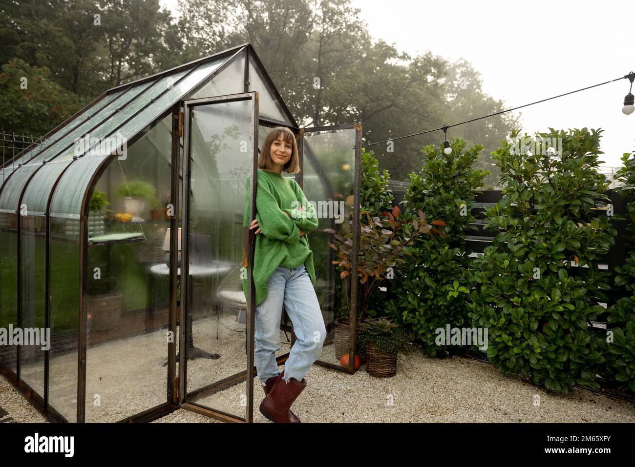 Donna vicino alla serra sul cortile Foto Stock