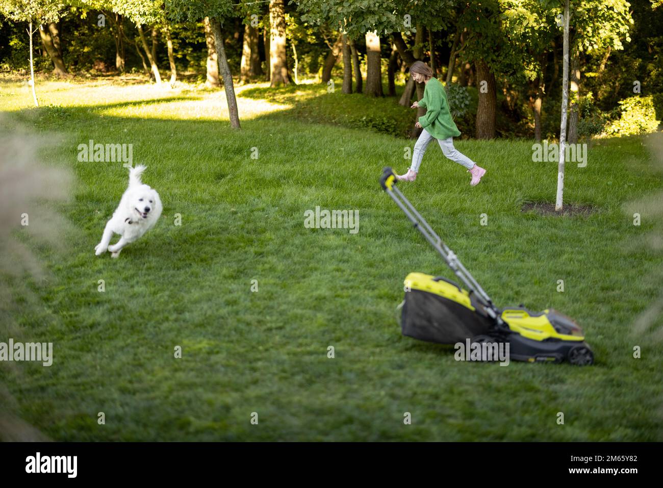 La donna gioca con il suo cane sul cortile mentre fa giardinaggio Foto Stock