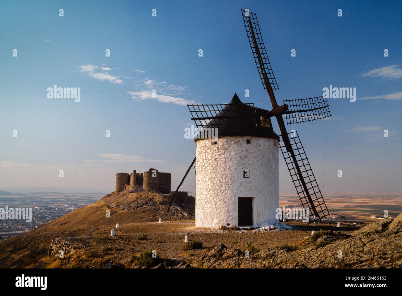 Spagna mulino a vento, vista di un mulino a vento storico e castello situato su una collina in Consuegra che domina la pianura di la Mancha, Castilla-la Mancha, Spagna Foto Stock