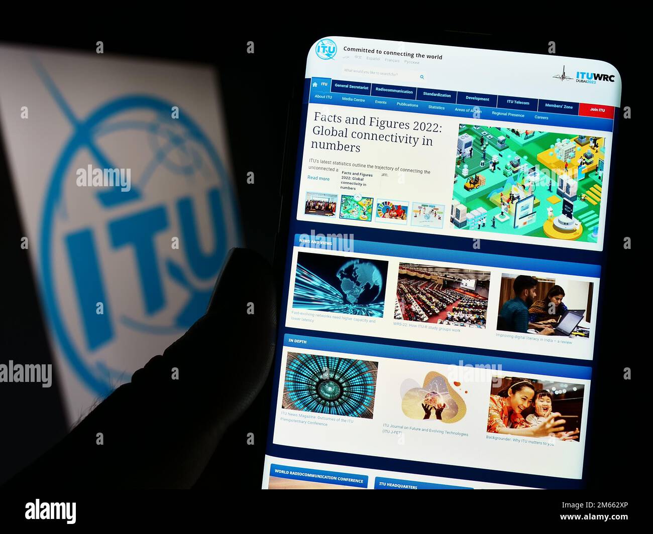 Persona che tiene il cellulare con la pagina web dell'Unione Internazionale delle Telecomunicazioni (ITU) sullo schermo davanti al logo. Messa a fuoco al centro del display del telefono. Foto Stock