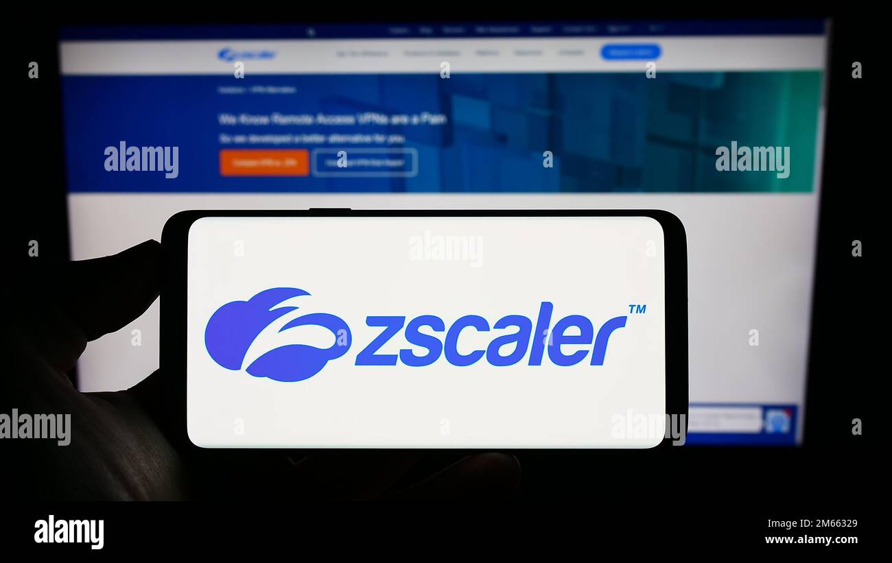 Persona che tiene il cellulare con il logo della società di sicurezza sul cloud degli Stati Uniti Zscaler Inc. Sullo schermo di fronte alla pagina web aziendale. Messa a fuoco sul display del telefono. Foto Stock