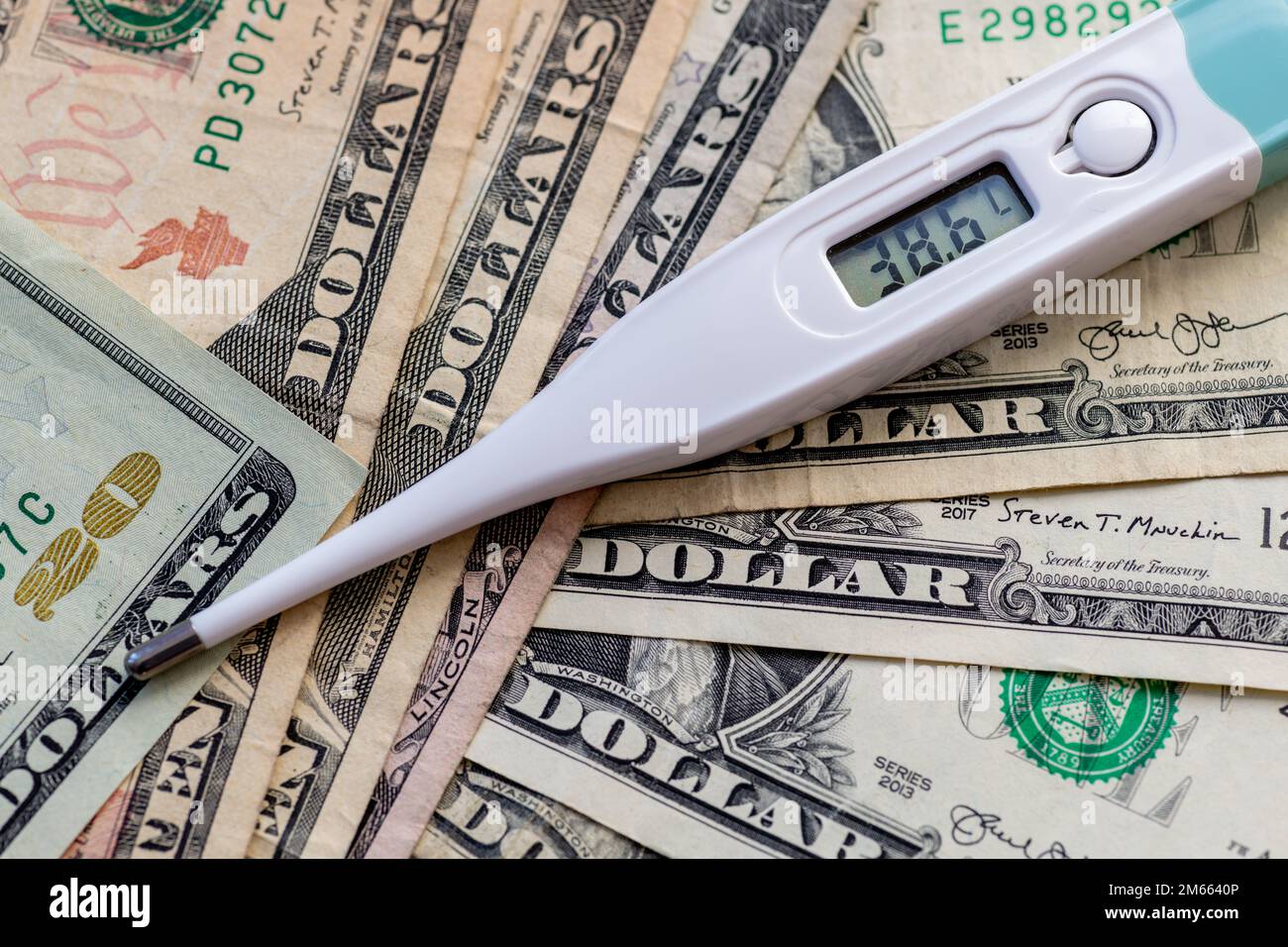 Un termometro sulla parte superiore di un mazzo di fatture del dollaro. Assistenza sanitaria, concetto di costo medico. Foto Stock