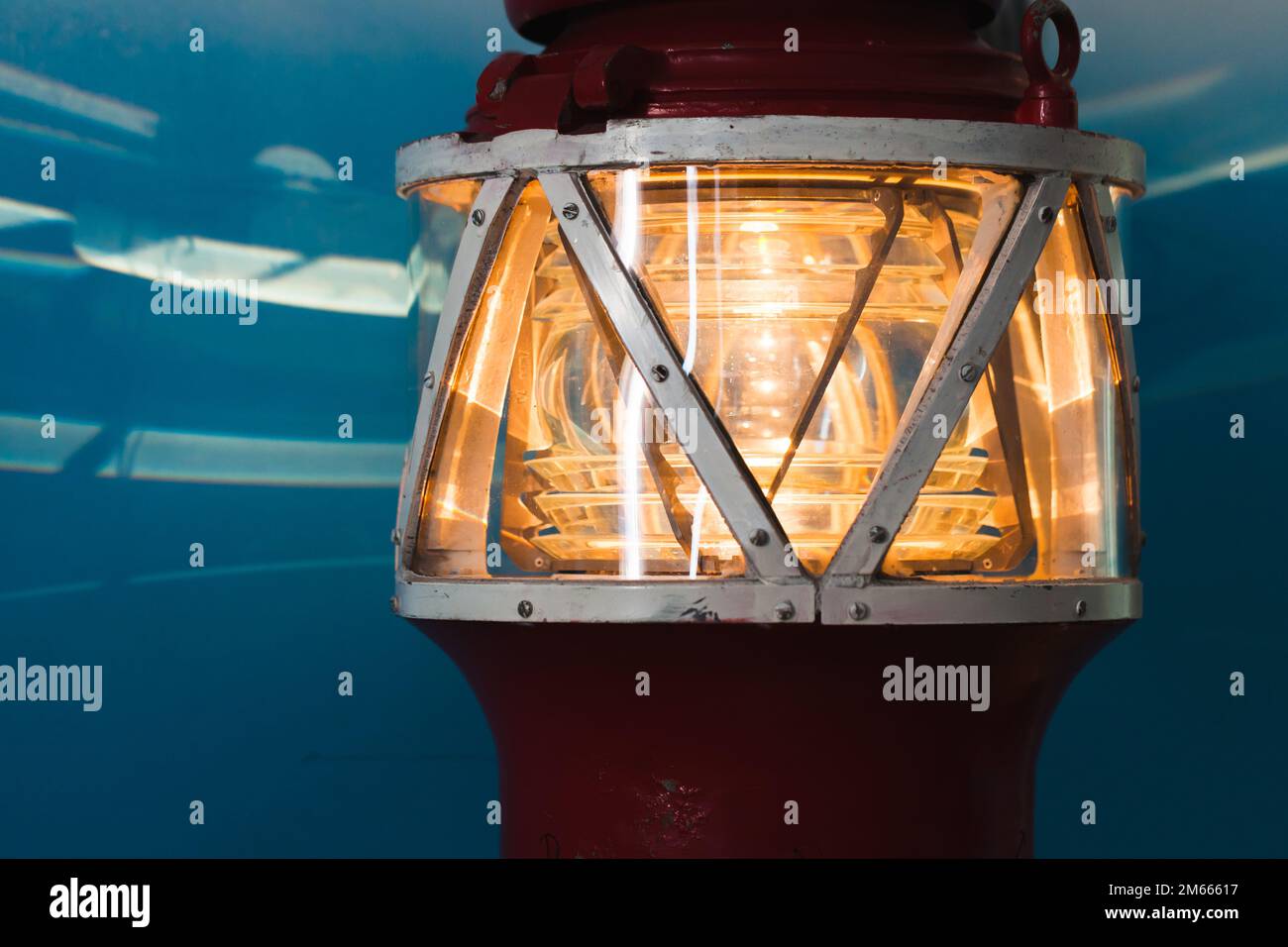 Parte superiore di un faro con faro giallo in struttura metallica su sfondo blu Foto Stock