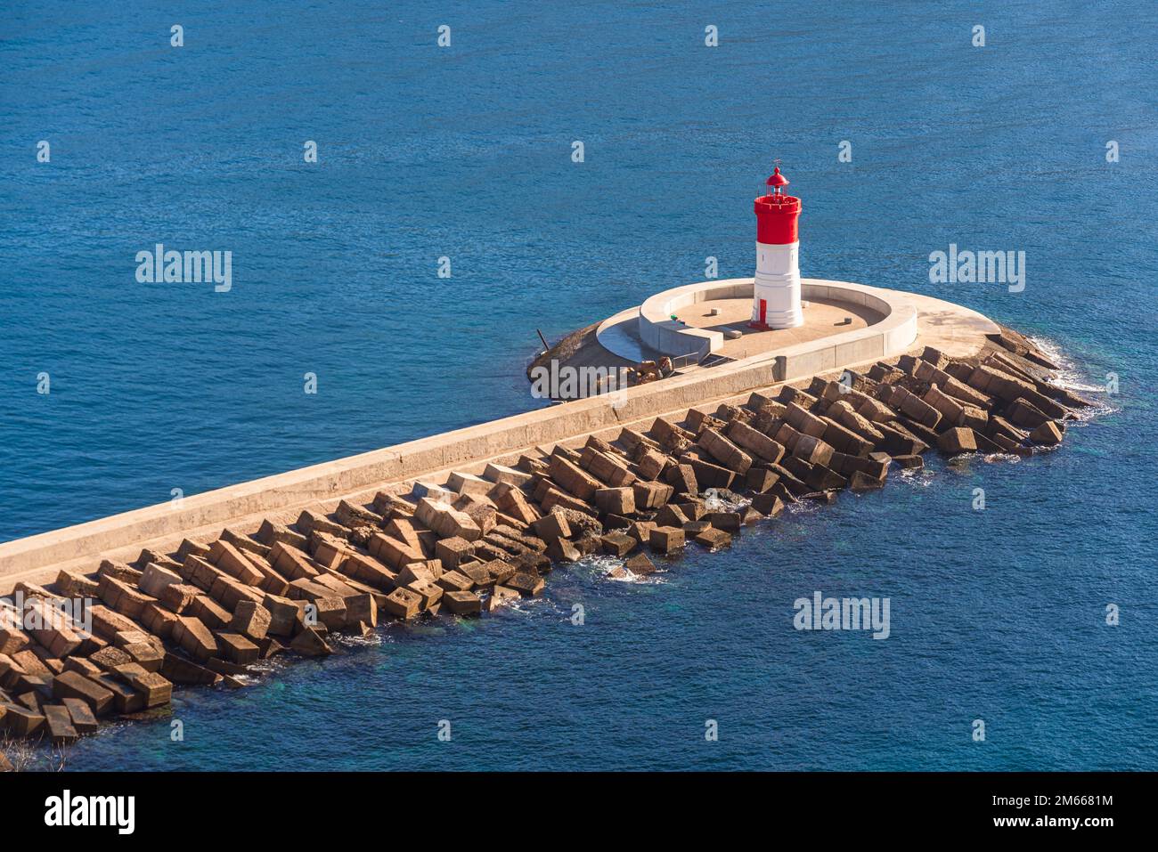 Faro rosso e bianco alla fine di un frangiflutti Foto Stock