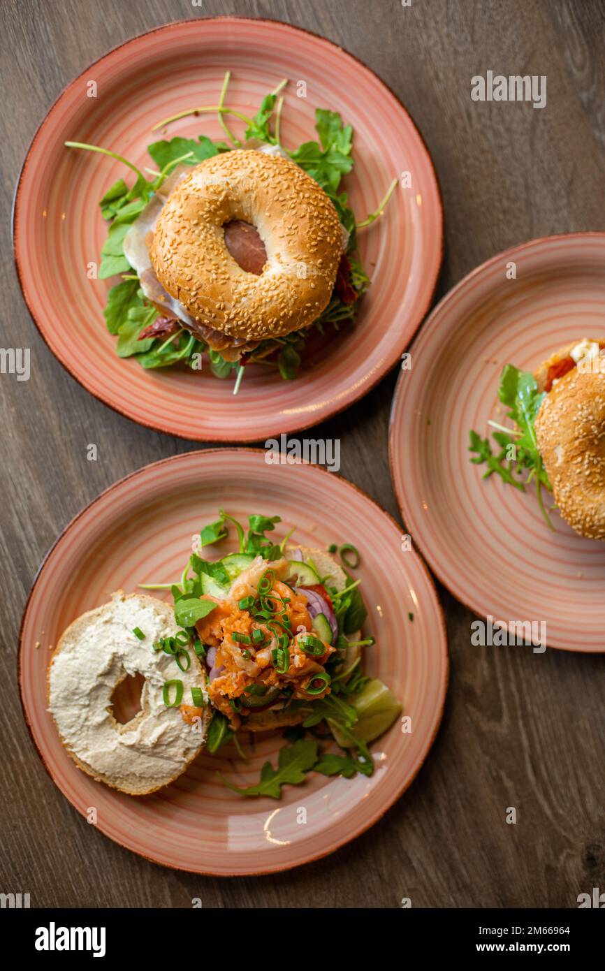 Verticale varie deliziose ciambelle al sesamo hamburger con formaggio, ripieno di carne, ripieno di verde, salsa servita su piatti Foto Stock