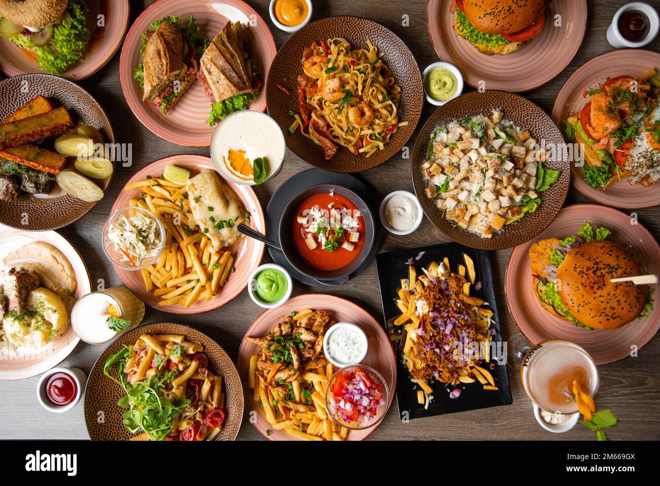 Abbondante snack e fast food su tavolo in legno nel ristorante. Nuovo menu del ristorante e bevande alcoliche nella caffetteria. Full frame Foto Stock