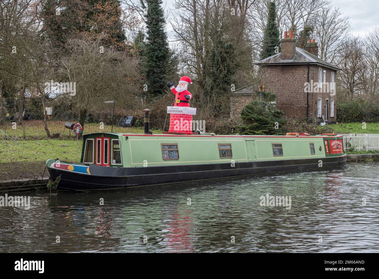 Blow up Babbo Natale giocattolo sul tetto di una barca ormeggiata canale (foto scattata il giorno di Natale) sul Canal Grand Union a Hanwell, Londra, Regno Unito. Foto Stock