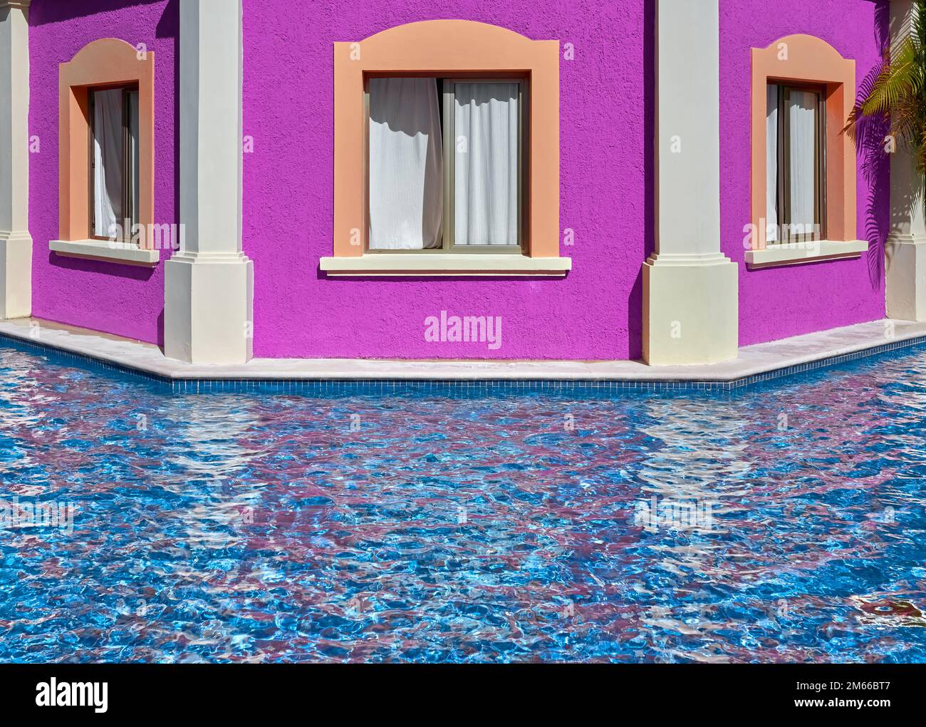 Edificio con facciata rosa con finestre vicino alla piscina. Foto Stock