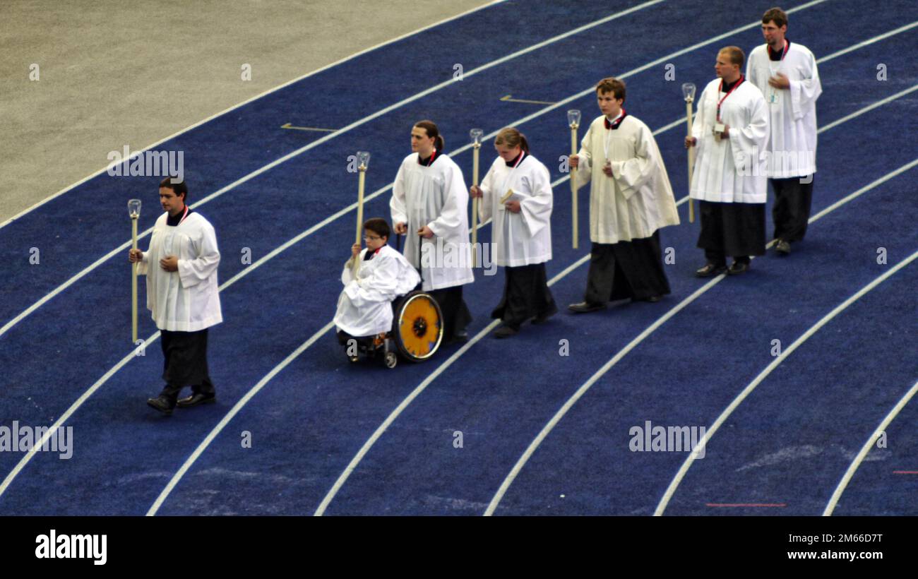 Bedikt XVI im Berliner Olympia-Stadion Josef Ratzinger Meßdiener mit Kerze auf der Laufbahn. Ein Meßdiener sitzt im Rollstuhl. Foto Stock
