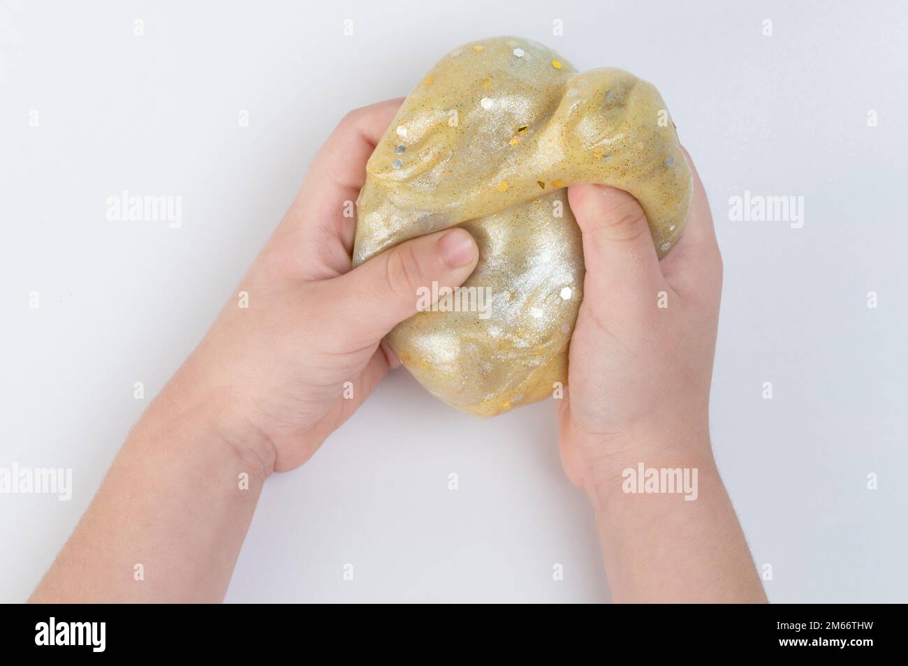 Bambini mano squeeeze palla oro con glitter isolato su sfondo bianco studio Foto Stock