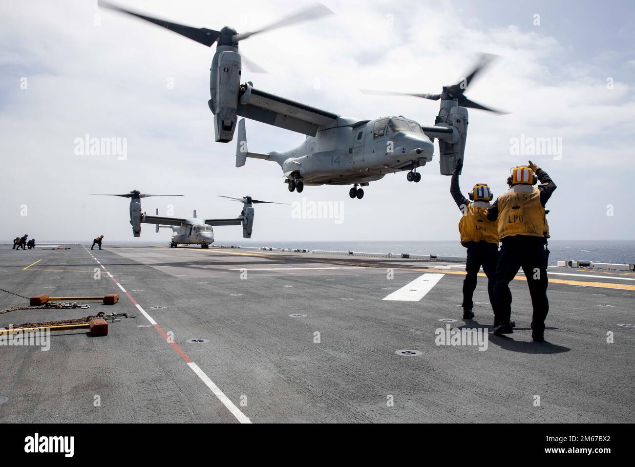 220204-N-VS068-2049 OCEANO PACIFICO (11 aprile 2022) – Aviation Boatswain’s Mate (Handling) Airman Darien Haq, a sinistra, E Aviation Boatswain’s Mate (Handling) 2nd Class Colin Fidel dirige un MV-22 Osprey, assegnato a Marine Medium Tiltrotor Squadron (VMM) 362, sul ponte di volo della nave d’assalto anfibio USS Makin Island (LHD 8), aprile 11. I piloti eseguono qualifiche di atterraggio sul ponte per praticare decolli e atterraggi a bordo. Makin Island sta conducendo operazioni di routine nella U.S. 3rd Fleet. Foto Stock