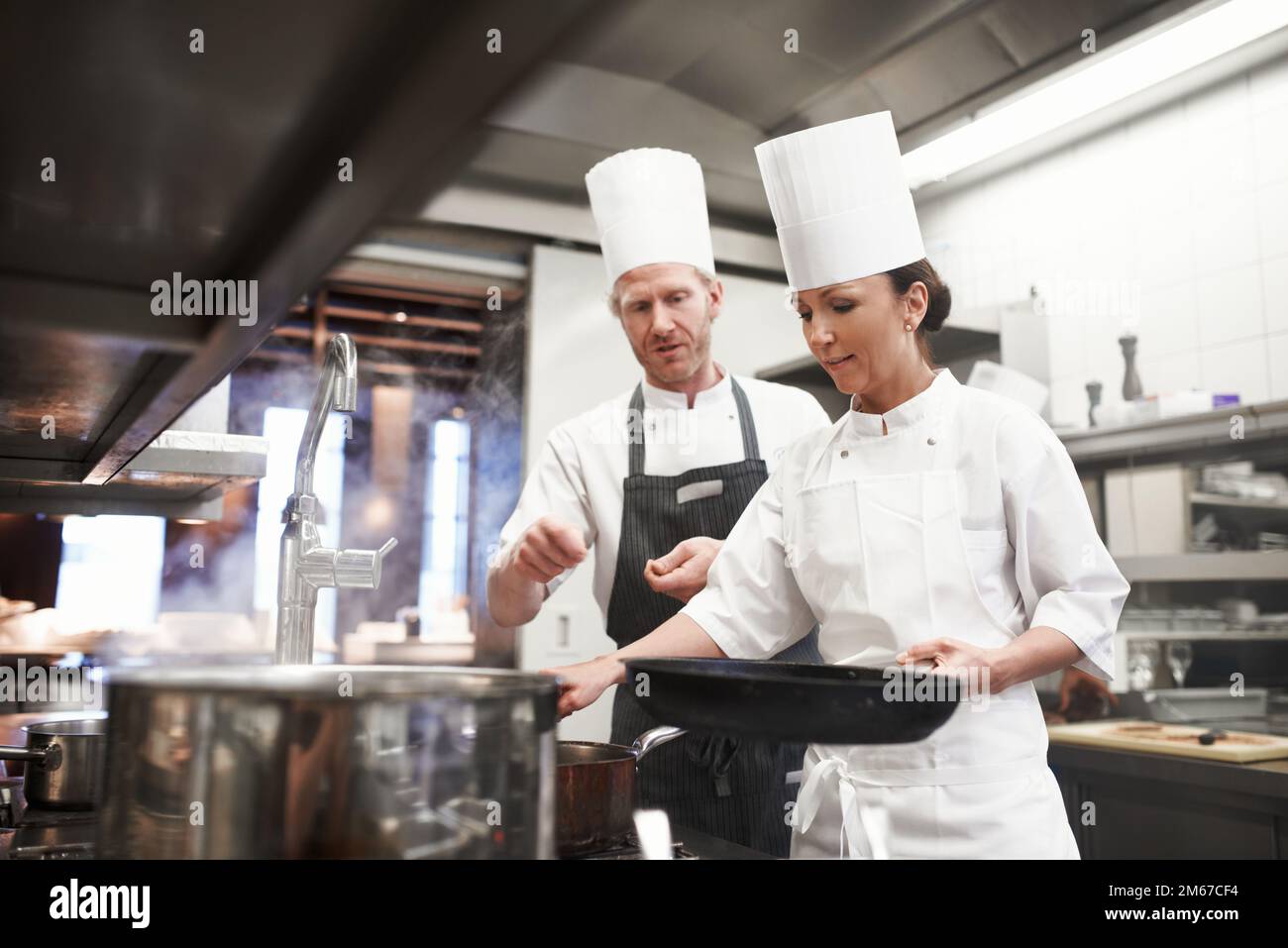 Passando sulla sua conoscenza culinaria. il lavoro interno di una cucina professionale. Foto Stock