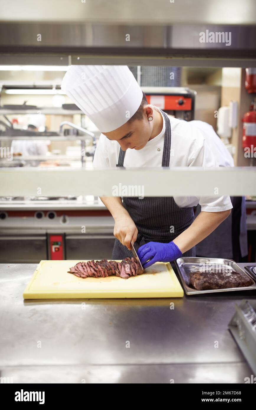 Preparare il pezzo di manzo perfetto. chef che preparano un servizio di pasto in una cucina professionale. Foto Stock