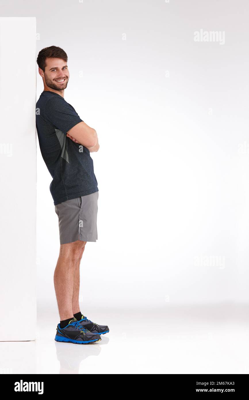 Ive non ha avuto niente di cui preoccuparsi. Studio shot di un giovane sorridente che si appoggia casualmente contro un tabellone vuoto. Foto Stock