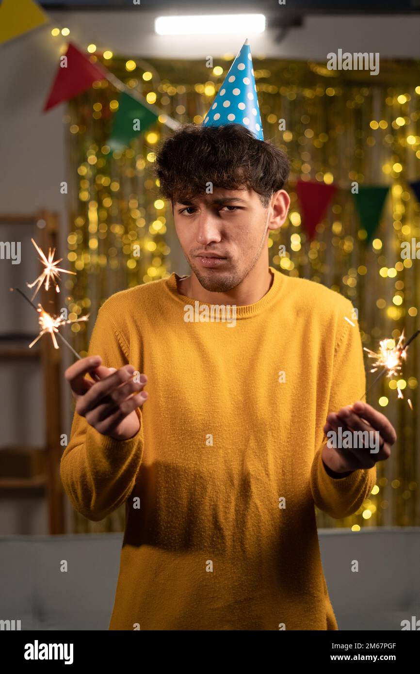 Uno studente maschile triste e cupo con gli sparklers festeggia il suo compleanno, si stanca dopo una notte insonne, si incontra con gli amici a casa. Foto Stock